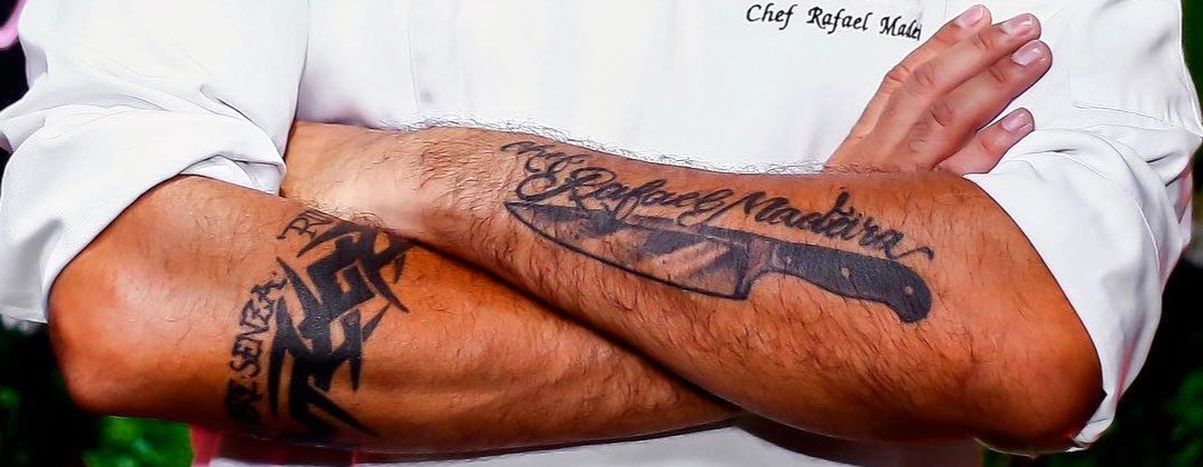 Braços cruzados do Chef Rafael Madeira com a tatuagem da faca e do nome