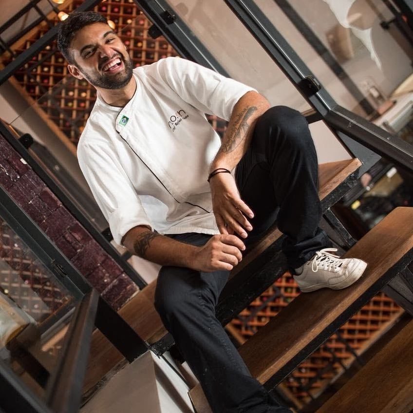 Chef Rafael Madeira sorrindo na escada da adega do NOAH