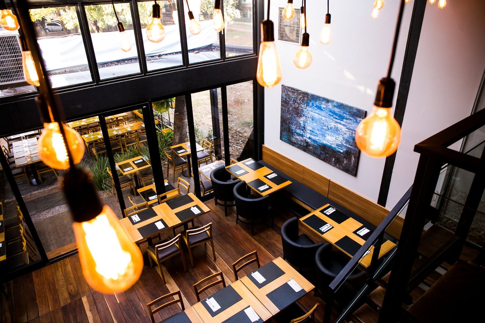 Vista do mezanino do NOAH Garden Bar: lâmpadas pendentes sobre o salão